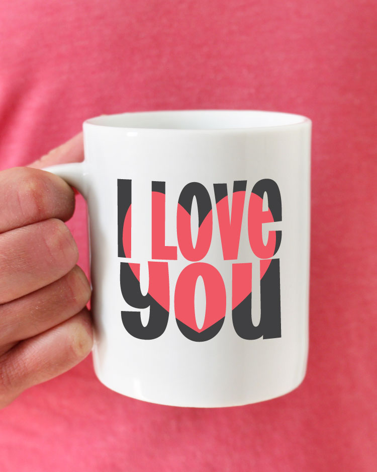 Man in pink shirt holding coffee mug with I love you block out design