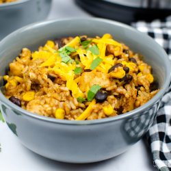 Grey ceramic bowl wtih forks and instant pot in background. Chicken burrito bowl recipe inside grey bowl