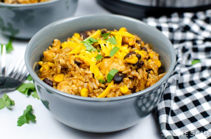 Grey ceramic bowl wtih forks and instant pot in background. Chicken burrito bowl recipe inside grey bowl