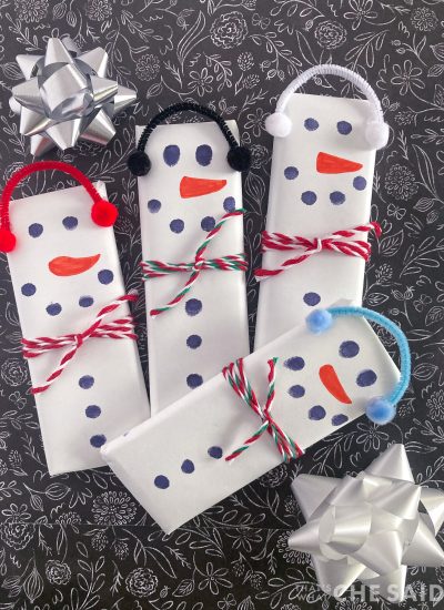 4 snowman candy bars on black background with bows vertical format