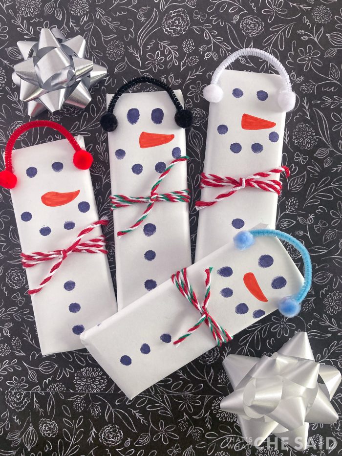 4 snowman candy bars on black background with bows vertical format