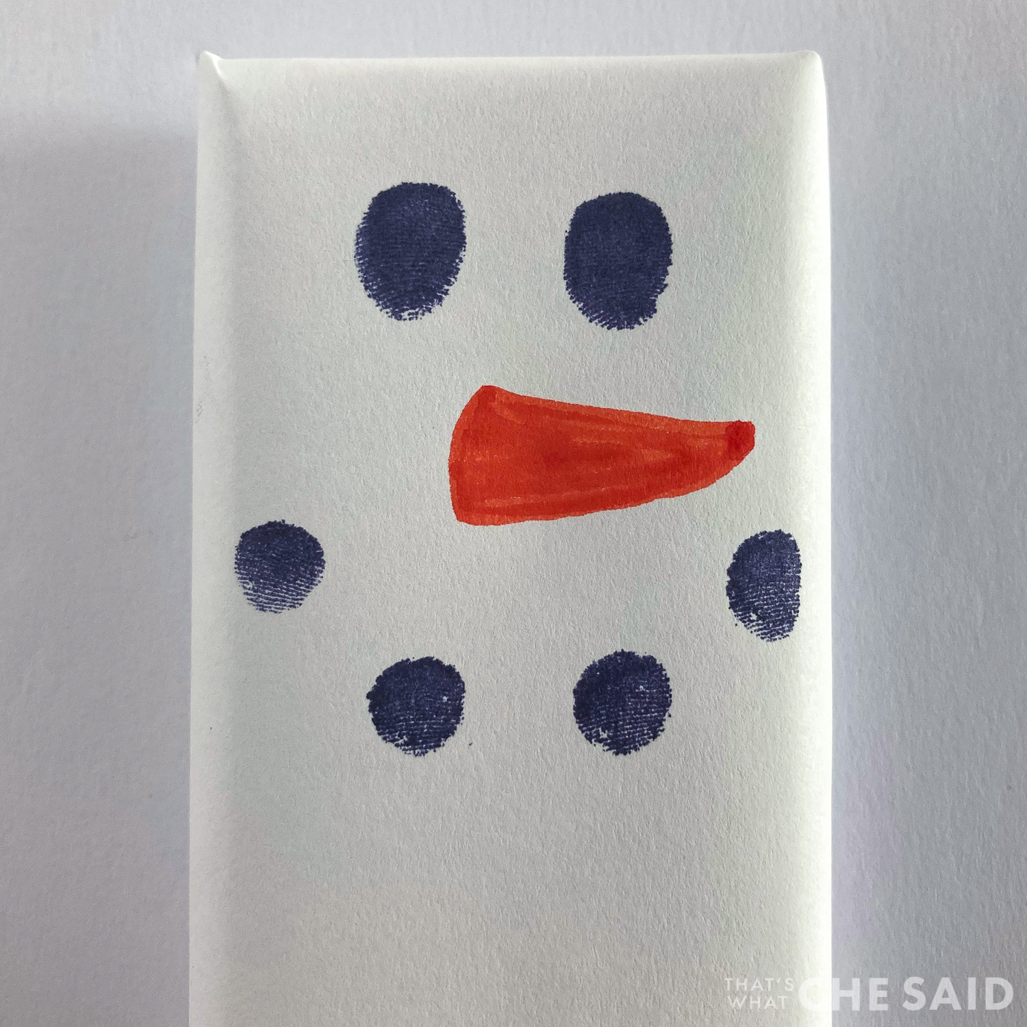 Close up of candy bar snowman face with eyes, carrot nose and coal mouth