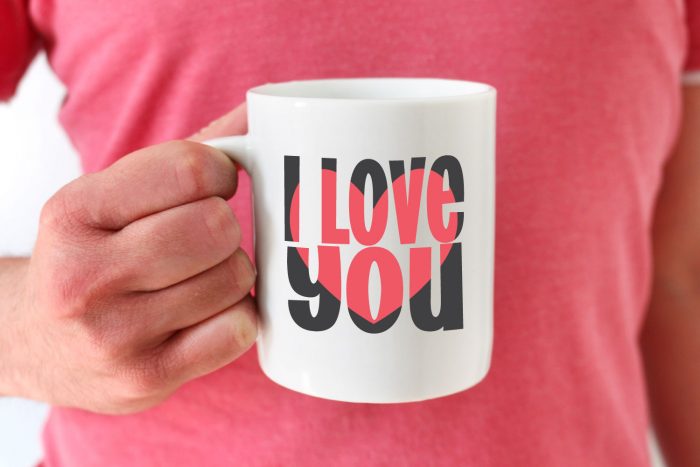 two tone block out i love you svg design on a white mug held by a man in pink shirt