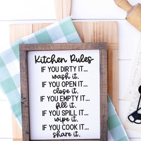 White wood with Cutting Board, kitchen towel, rolling pin and sign that has kitchen rules svg applied