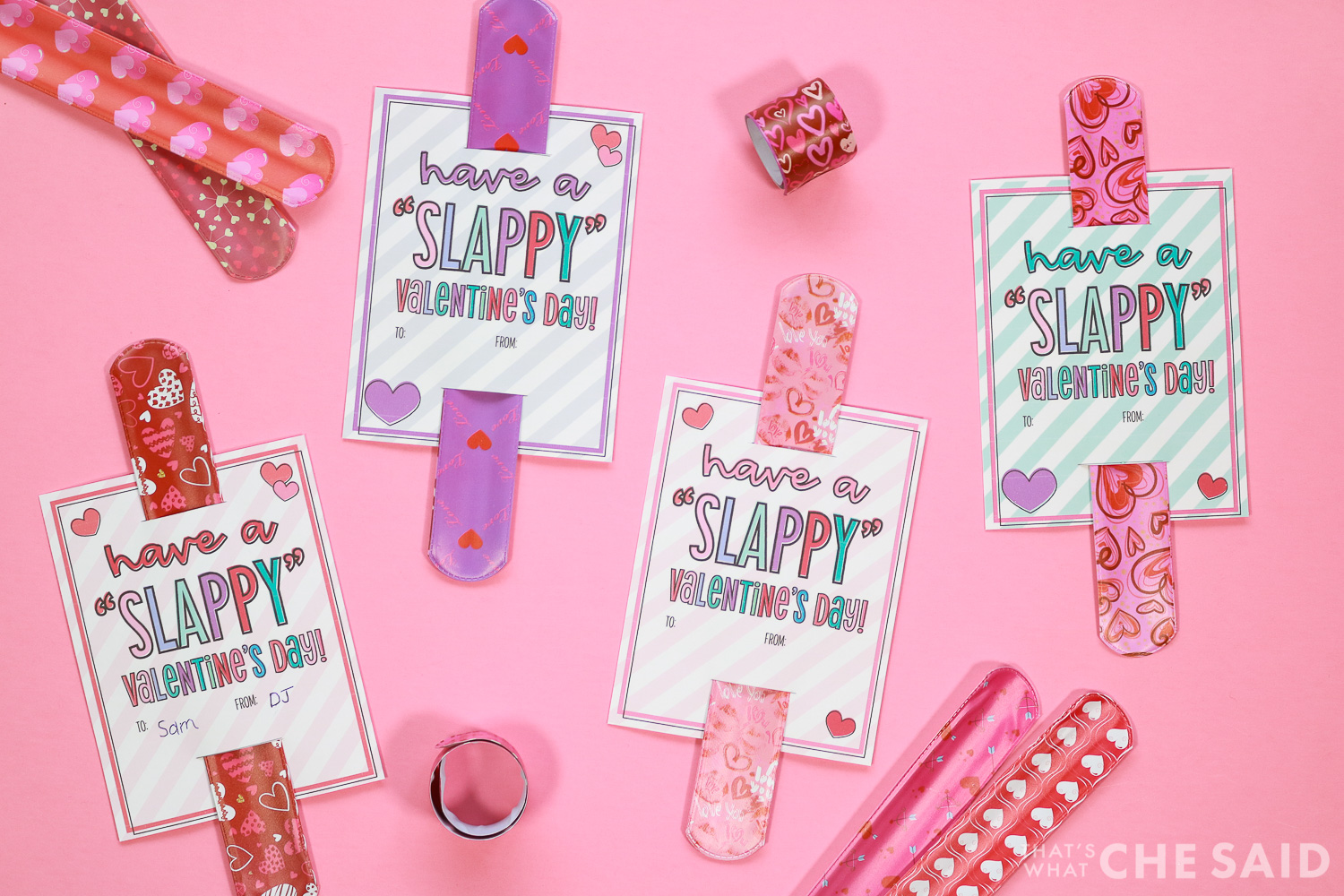 Slap Bracelet Valentines assembled on a pink background with extra slap bracelets surrounding them