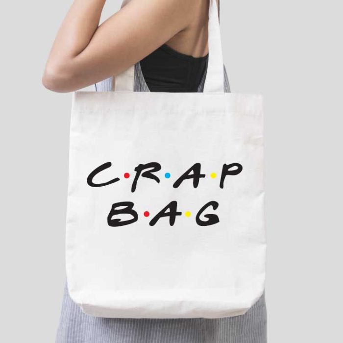 Woman holding white tote bag with "Crap Bag" in FRIENDS tv show font applied with iron on