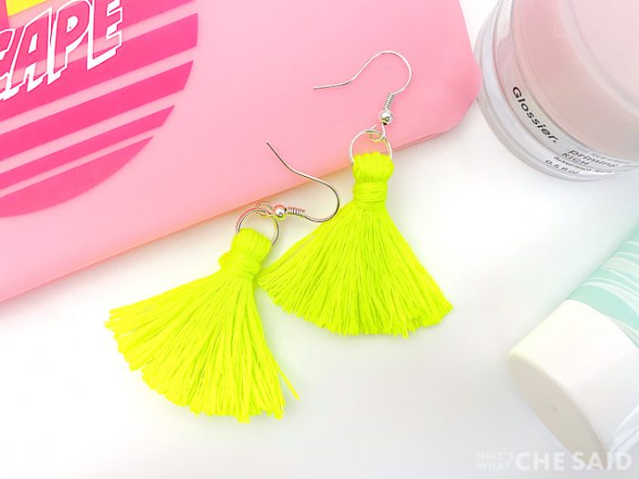 Completed bright yellow tassel earrings amongst some make up products