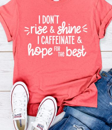 Coral shirt, jeans and white converse with "I don't rise and shine I caffeinate and hope for the best" written on the shirt in vertical format