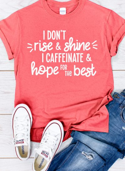 Coral shirt, jeans and white converse with "I don't rise and shine I caffeinate and hope for the best" written on the shirt in vertical format