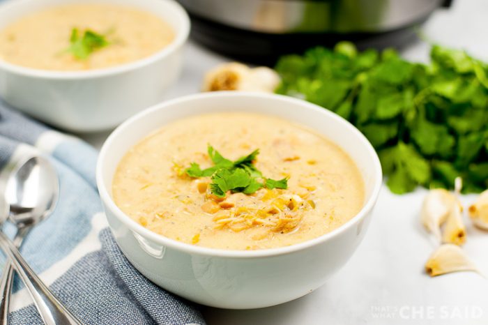 Instant Pot white chicken Chili in bowl with Instant pot and cilantro in background