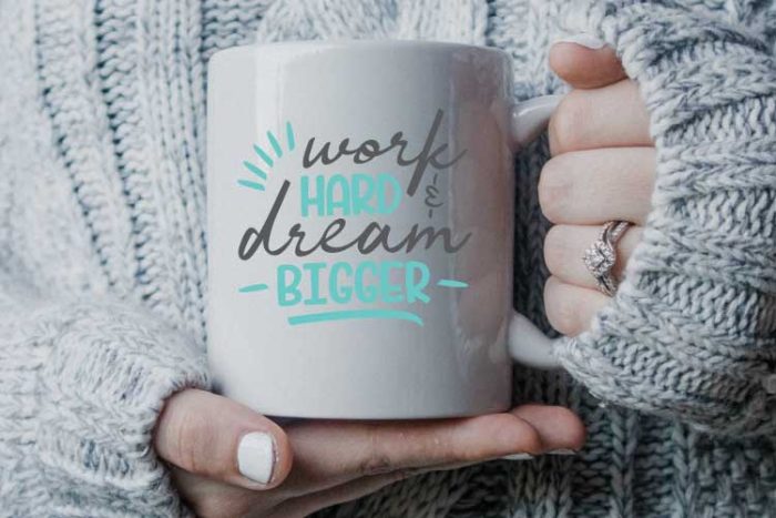 Woman is sweater holding coffee mug with motivational svg applied in vinyl