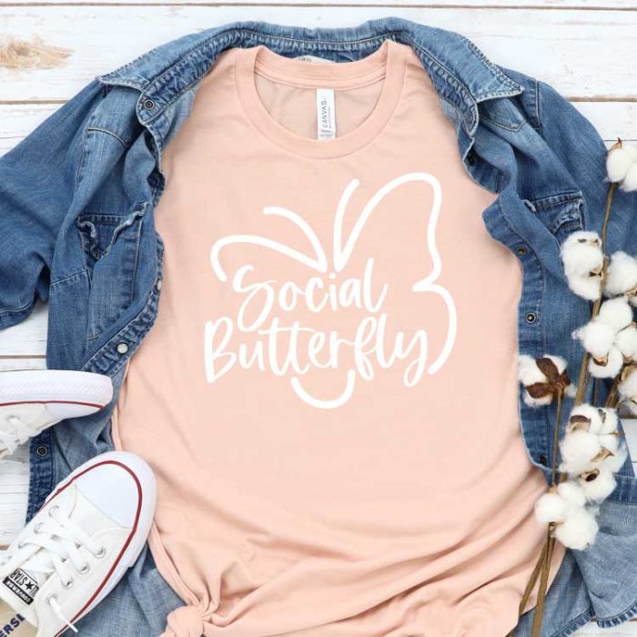 Peach T-shirt with Social Butterfly Design with Demin shirt behind and White Converse - square Format