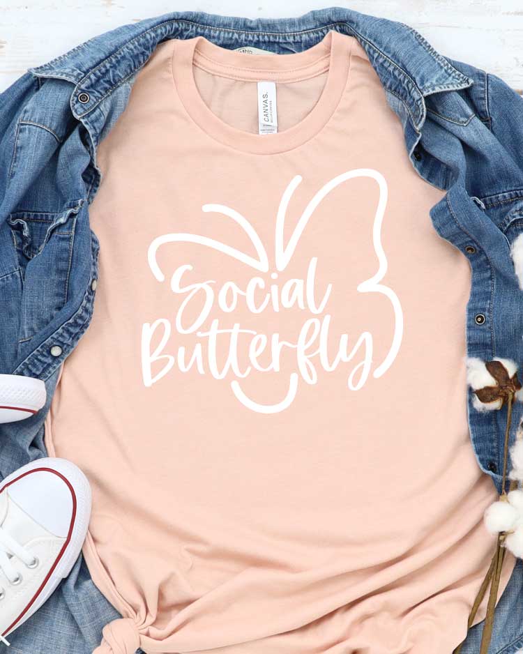 Peach T-shirt with Social Butterfly Design with Demin shirt behind and White Converse - Featured