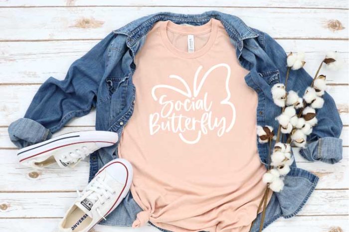 Peach T-shirt with Social Butterfly Design with Demin shirt behind and White Converse - Horizonal Format