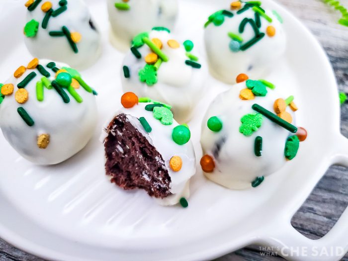 Oreo truffles with St. Patrick's Day sprinkles on a white platter with one bitten into