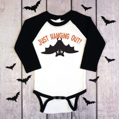 black and white raglan onesie with Just hanging out bat design on wood background