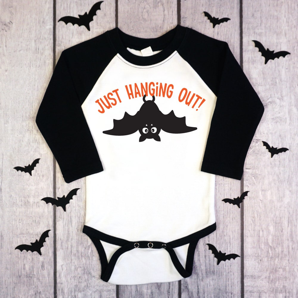 black and white raglan onesie with Just hanging out bat design on wood background