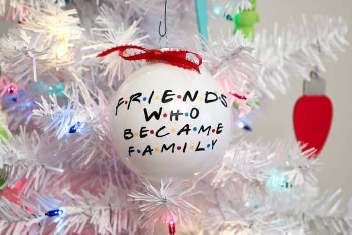 White ornament on white tree with colored lights
