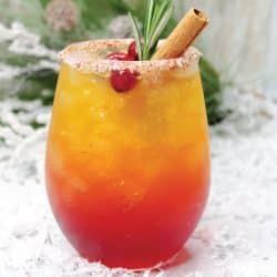 naughty and nice holiday cocktail in a stemless wine glass with fake snow and greenery