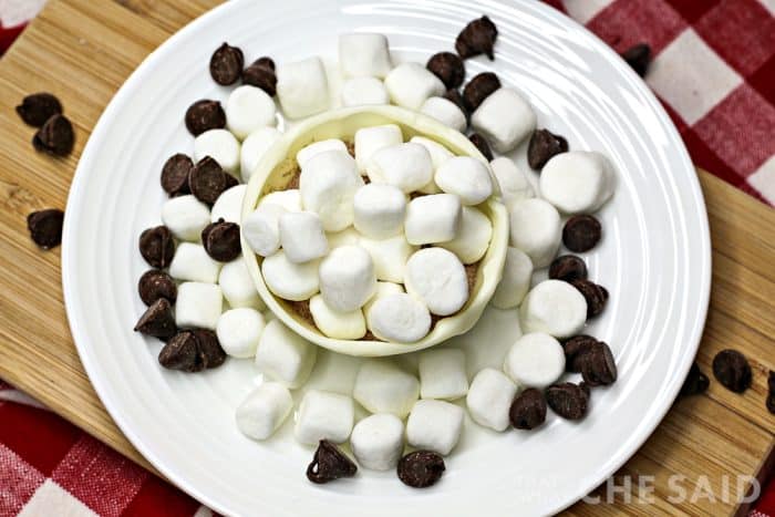 Half shell of snowman hot chocolate bomb filled with hot chocolate mix and mini marshmallows