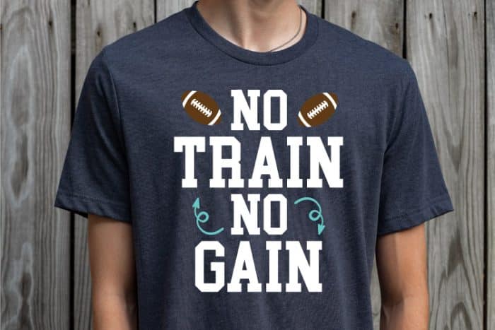 Man wearing navy tshirt with "No train, no gain" design with footballs - horizontal orientation
