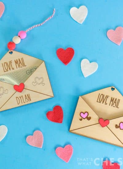 Blue background with heart confetti and two laser engraved and cut wooden gift card holders with valentine's day theme - square orientation