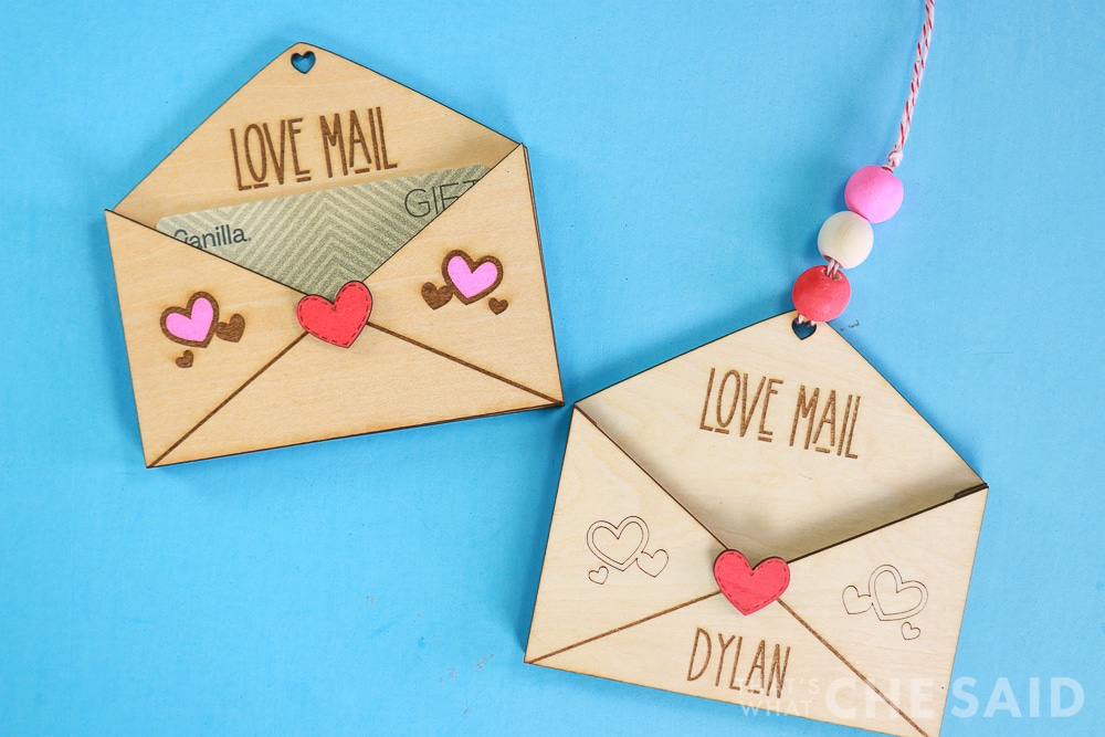 Blue background and two laser engraved and cut wooden gift card holders with valentine's day theme - Horizontal orientation