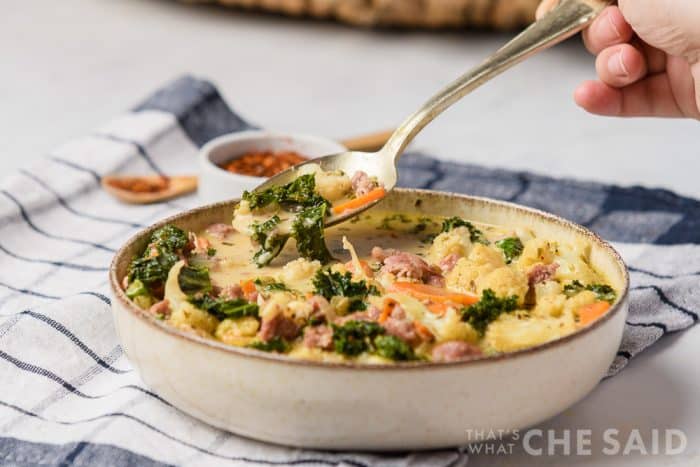 Scooping a spoonful of Sausage Kale Soup in Horizontal Format