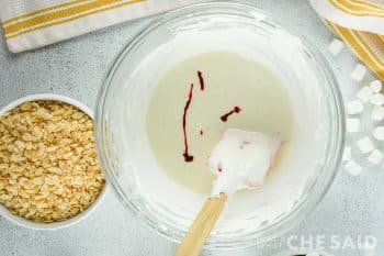 melted marshallow mixture in a bowl with yellow gel food coloring added.