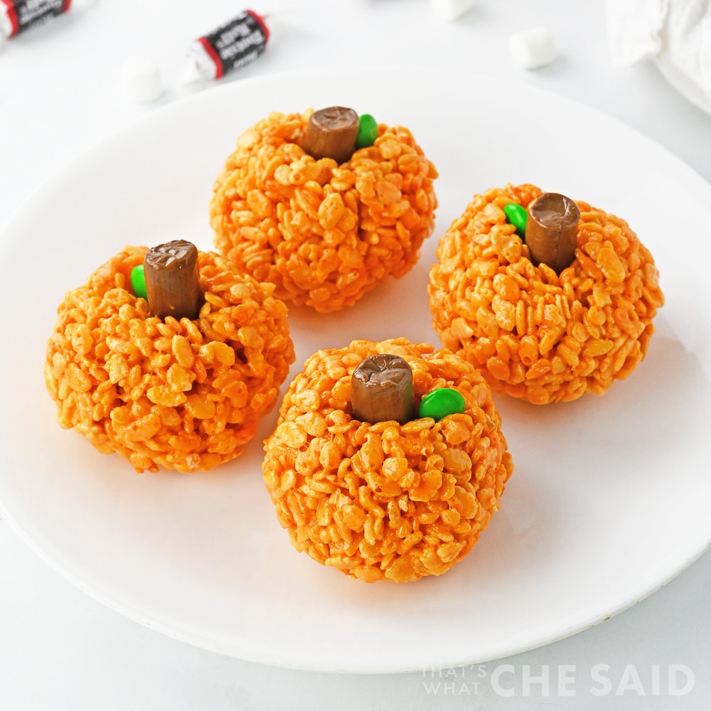 Rice Krispie treats on white plate with tooties rolls in background