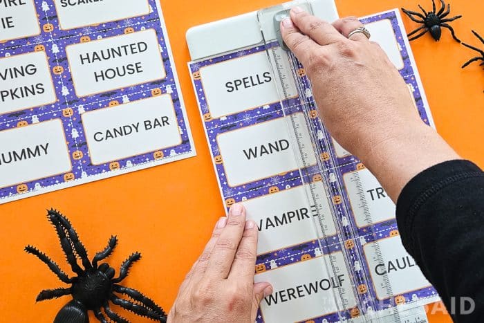 cutting sheets of halloween action charades printables wtih a paper cutter orange background with spiders