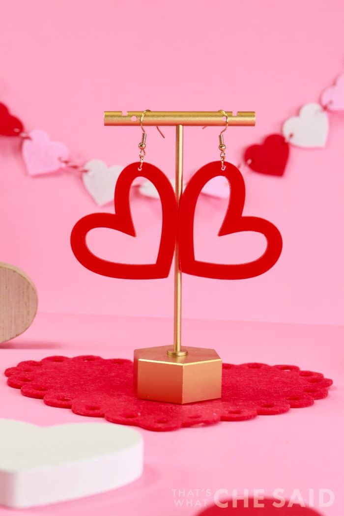 Red Whimsical Heart earrings cut from acrylic on xtool M1 hanging from earring stand