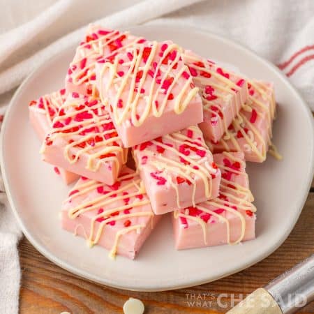 Valentine Sugar Cookie Fudge stacked on a white plate with towel - square