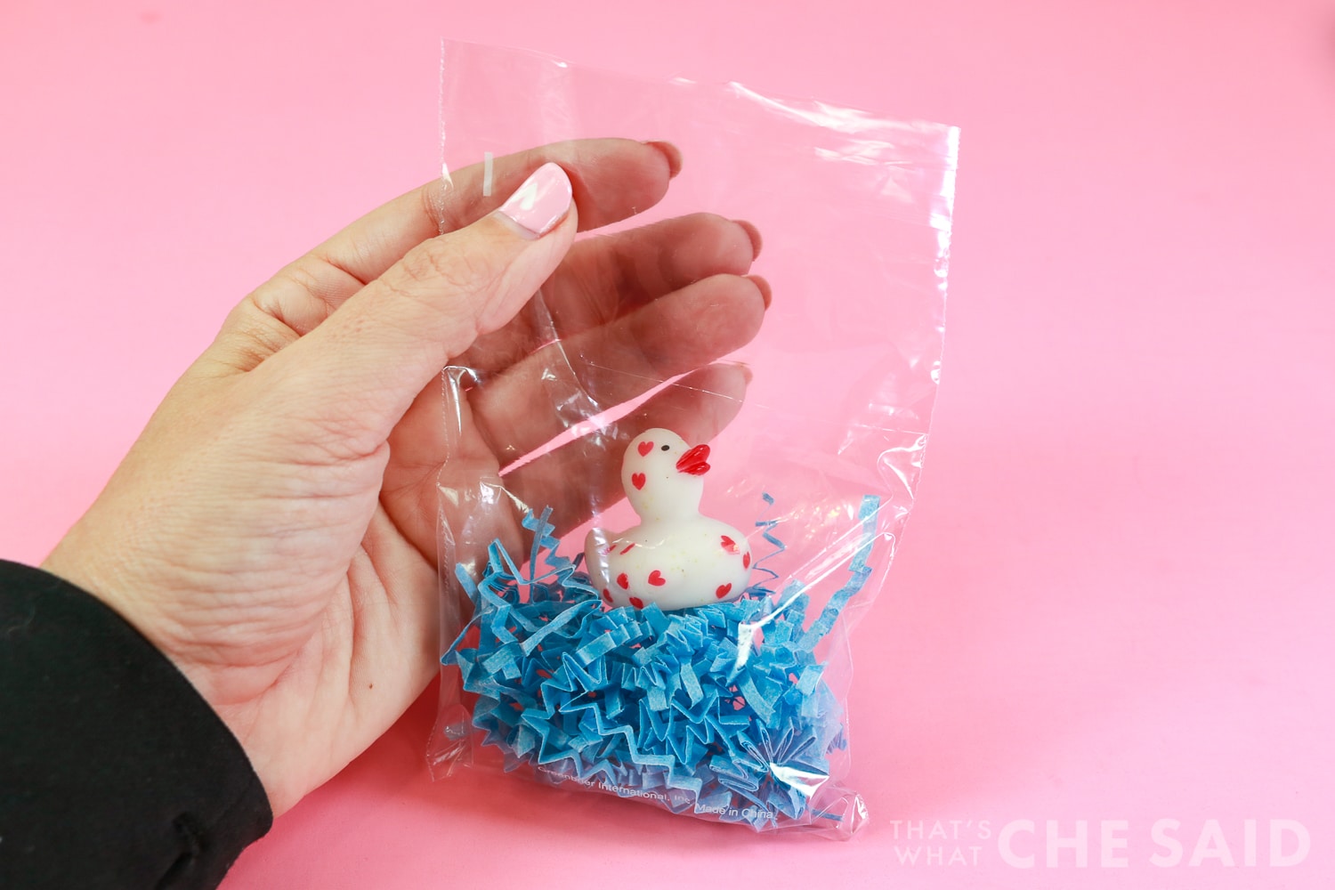 Plastic treat bag with blue crinkle paper and a valentine rubber duck inside