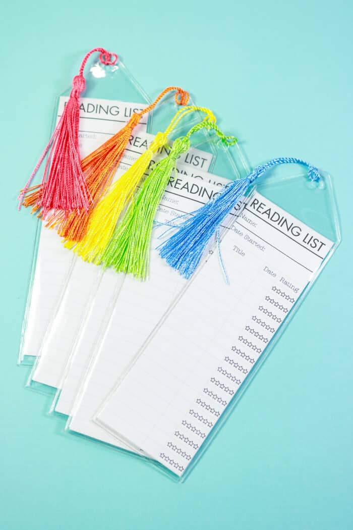 Reading log bookmarks with rainbow tassels ina pile oon an aqua background