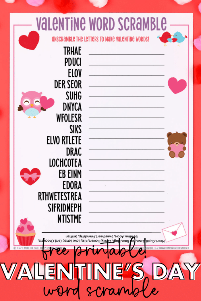 Photo of printed Valentine word scramble printable on red background with white, red and pink pom pom table scatter in vertical orientation