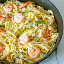 Square image of garlic butter shrimp alfredo in a skillet