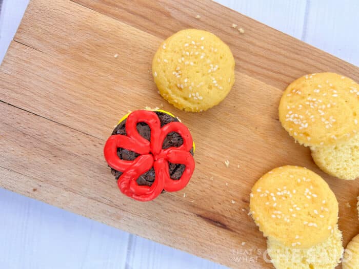 Adding red icing as ketchup to burger cupcake