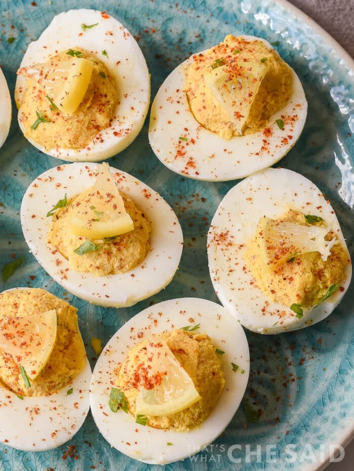 Spicy Deviled eggs close up with lemon wedges on blue plate