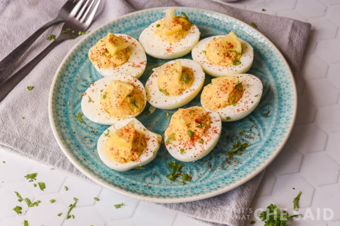deviled eggs on a blue plate with a fork and napkin