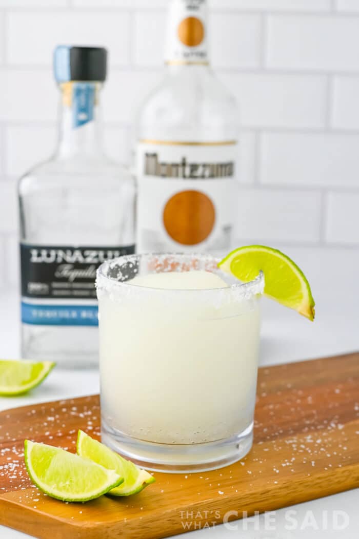 Frozen Limeade Margarita with lime garnish and bottles in background