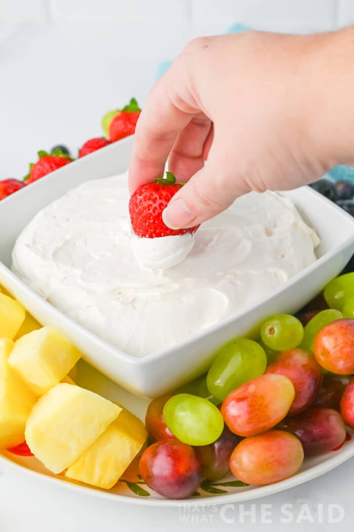 Hand dipping strawberry into Cool Whip Fruit Dip