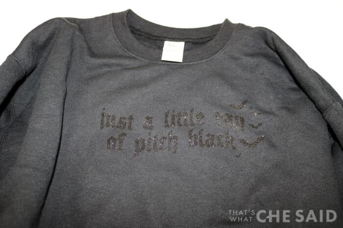 Black sweatshirt with glitter vinyl in the phrase "just a little ray of pitch black"