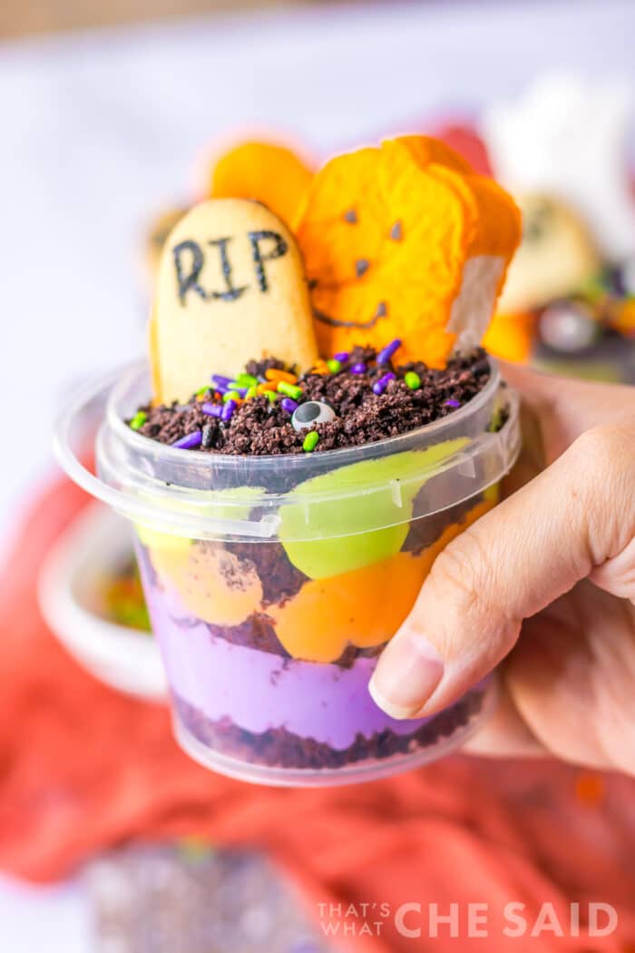A hand holding a halloween graveyard cake cup