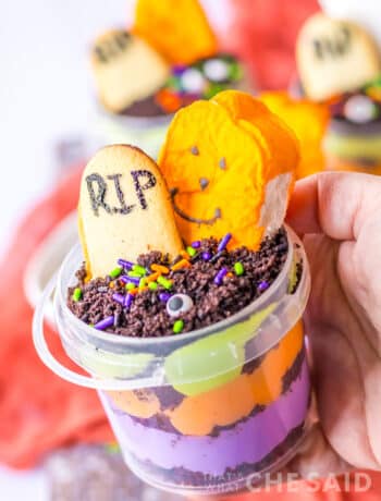 a hand holding a halloween graveyard treat cup