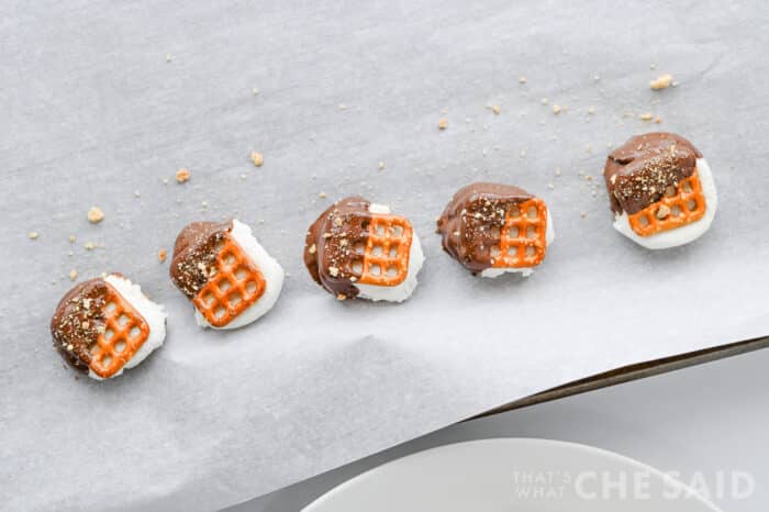Sprinkling crushed graham crackers on top of bites while chocolate is melted